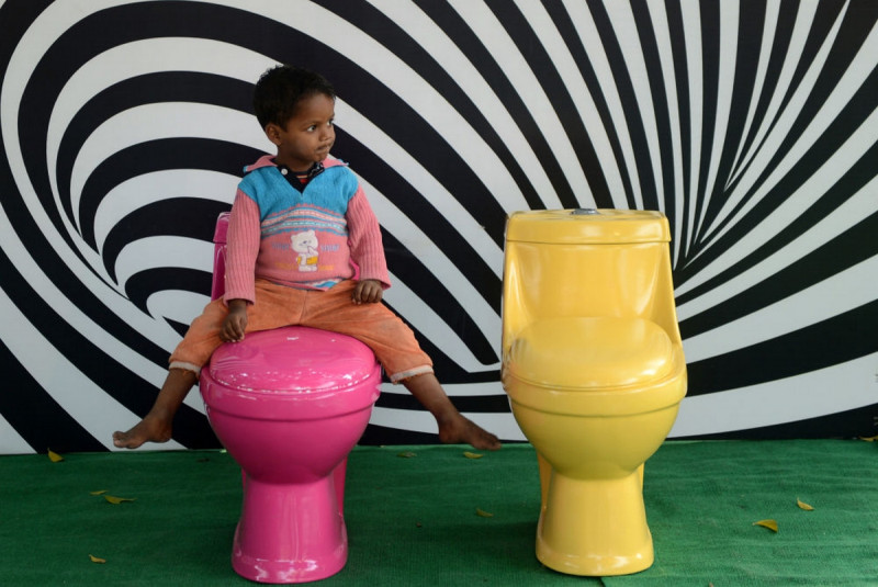 Мальчик в Нью-Дели сидит на унитазе во время кампании Туалеты — это красиво по случаю Всемирного дня туалета.  В индии проблема отсутствия туалетов стоит особенно остро. 